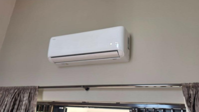 Wall-mounted split unit in a home, above the curtains