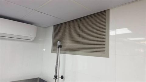 Wall-mounted split unit above a louvred vent