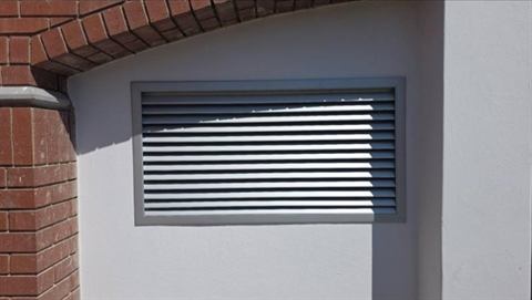Louvred ventilation grille in a brick wall