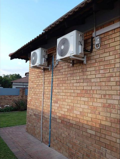 Two outdoor units on the side wall of a home