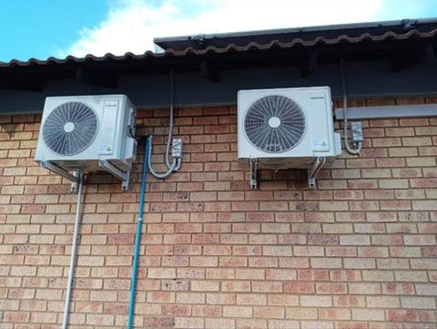 Two outdoor units under the roof eaves of a home