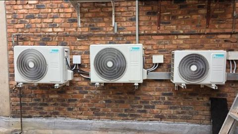 Three outdoor condensers on a face-brick wall