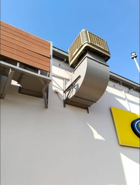 Evaporative cooler mounted high on a building wall